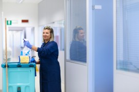 Portrait of happy professional female cleaner smiling in office